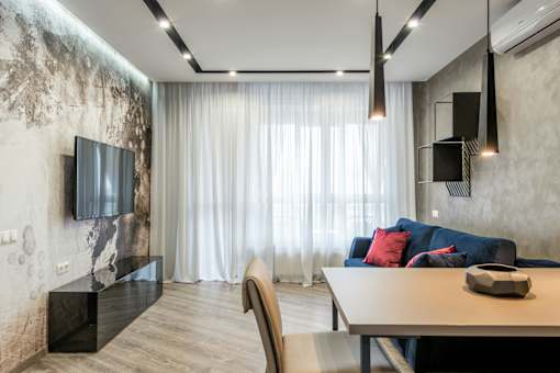 A modern living room with a blue couch and a flat screen TV mounted on the wall.