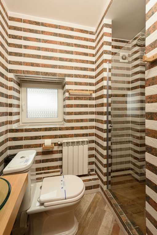 A bathroom with a toilet, tiled walls, and a window.