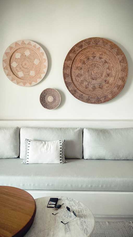 gray couch in front of white wall with wooden decorations hanging above