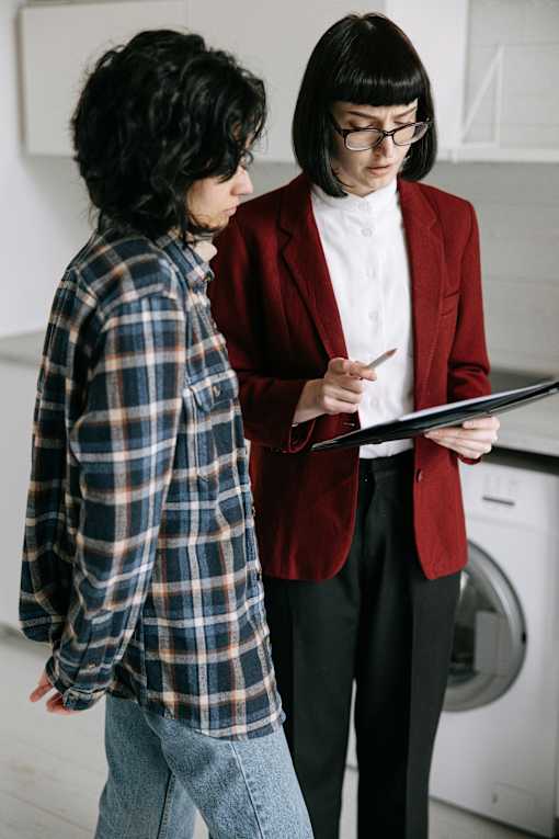 Two people in a laundry room, one holding a tablet.