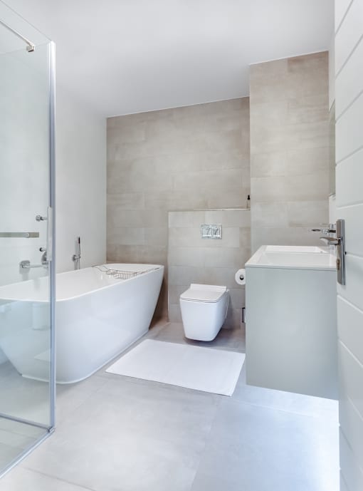 white bathtub with white walls, white floor, and white toilet