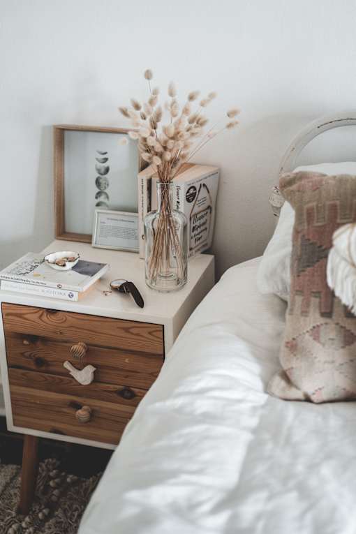 bed and bedside table with dried flowers