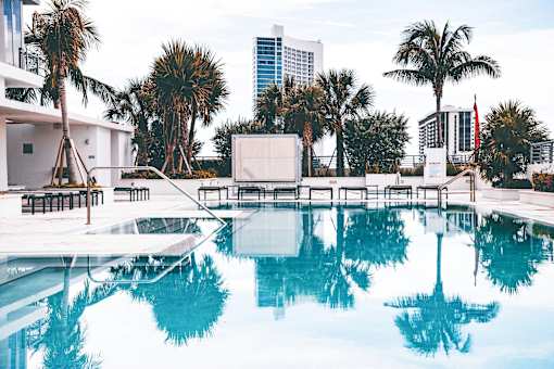 A pool with palm trees reflected in the water.