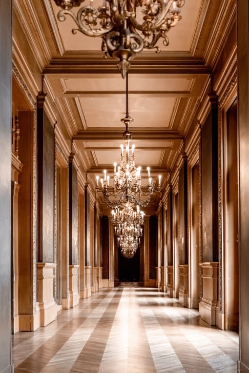 the hallway of the building is lined with columns and chandeliers