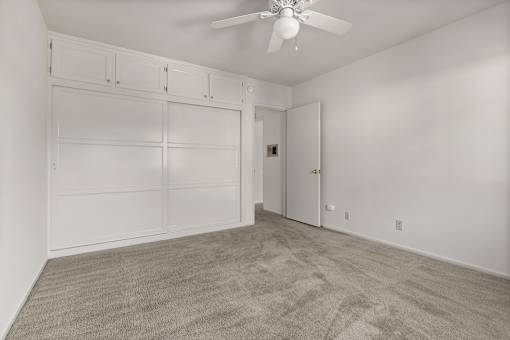 A room with a ceiling fan and a carpeted floor.