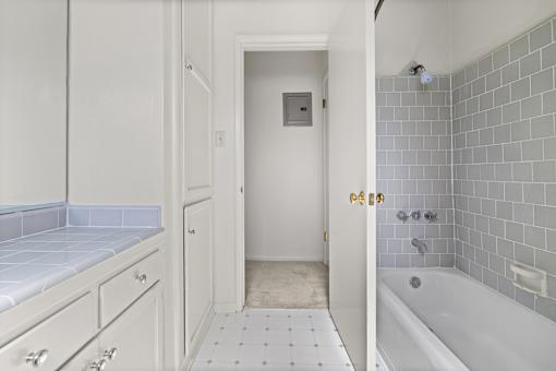 A white bathroom with a tiled floor and a white bathtub.