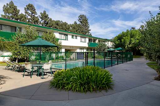A green umbrella is in front of a white building.