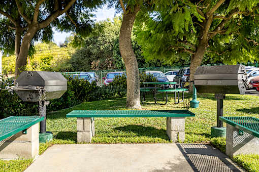 A park with green benches and trees.