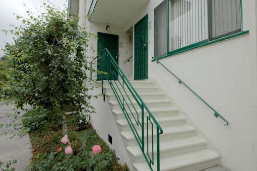 A white house with a green door and staircase.