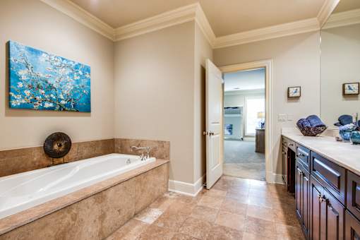 A bathroom with a large tub and a painting of a tree on the wall.