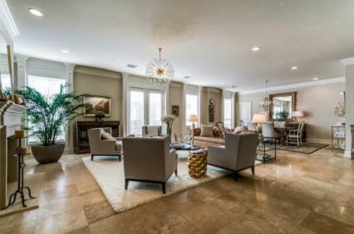 A living room with a large rug and a chandelier.