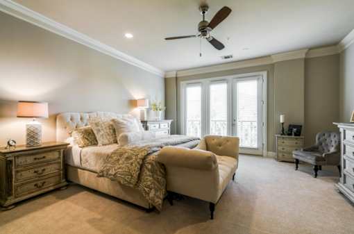 A bedroom with a large bed, a chair, and a dresser.