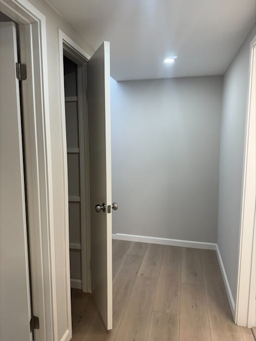 A white door is open to a room with wood flooring.