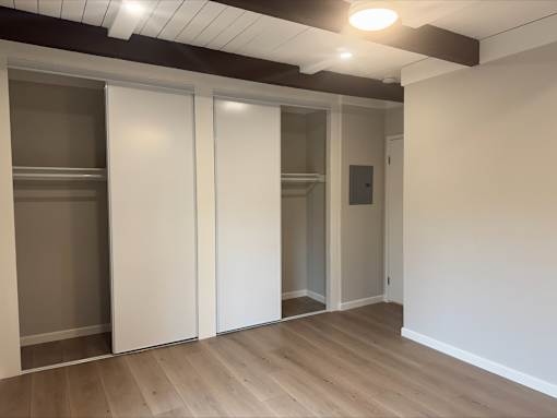 A room with a white wall and a brown ceiling with a sliding door.