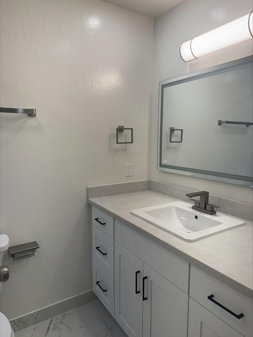 A bathroom with a white sink and a mirror above it.