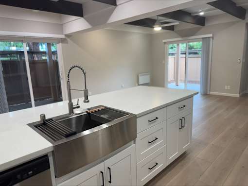 A modern kitchen with a stainless steel sink and white cabinets.