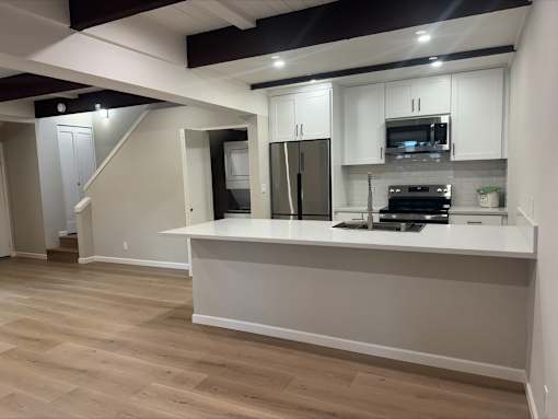 A kitchen with white cabinets and a wooden floor.