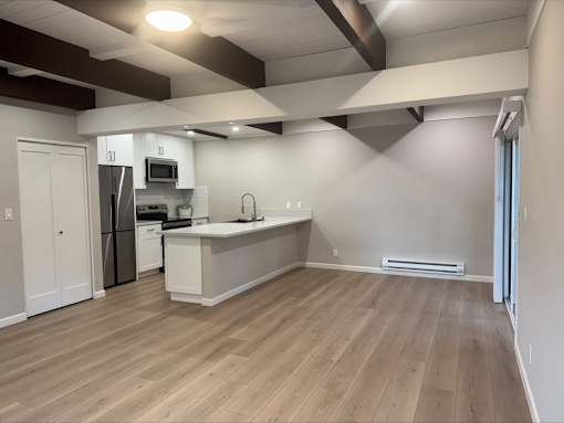A kitchen with a refrigerator, microwave, and sink.