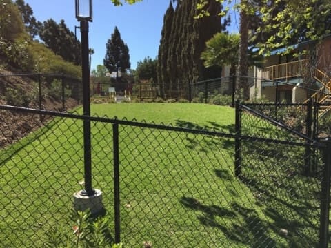 a yard with a chain link fence and a baseball field