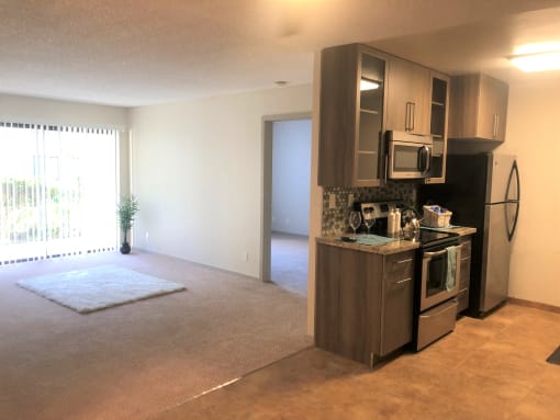 an empty living room with a kitchen with a stove and refrigerator