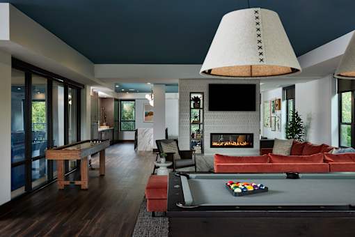A modern living room with a pool table and a fireplace.