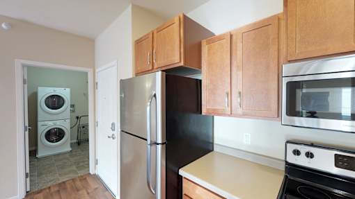 A kitchen with a black refrigerator and wooden cabinets.