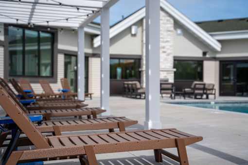 A row of wooden lounge chairs are arranged on a patio.