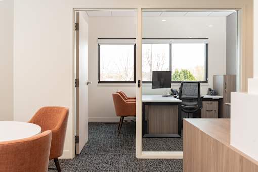 A room with a desk, chairs and a computer.