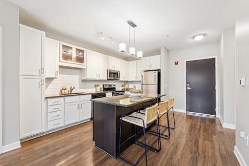 A kitchen with a dark wood floor and white walls.