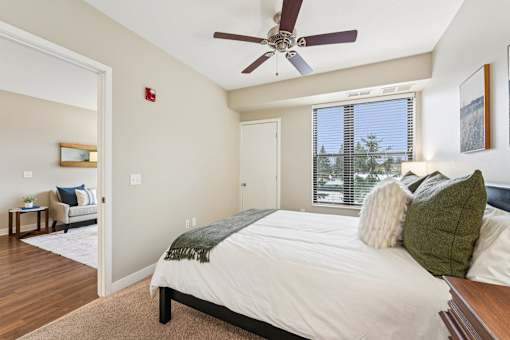 A bedroom with a bed, pillows, and a ceiling fan.