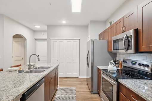 A kitchen with a granite countertop and stainless steel appliances.