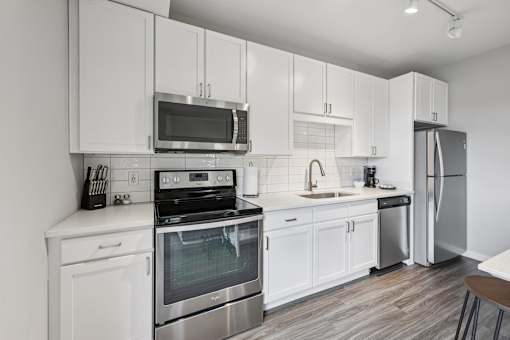 A modern kitchen with white cabinets and stainless steel appliances.
