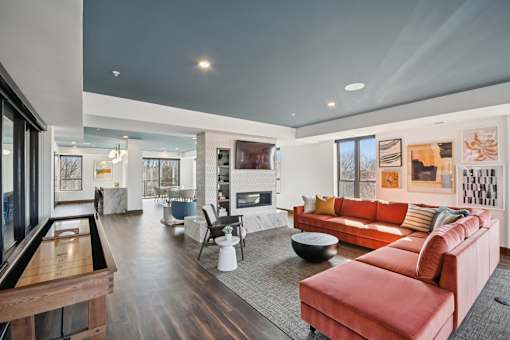 A modern living room with a pool table and a red couch.
