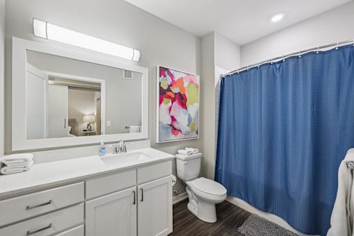 A bathroom with a white counter top and a blue shower curtain.