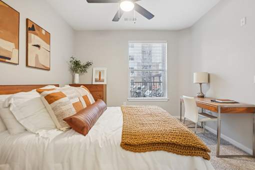 A bedroom with a bed, desk, and window.