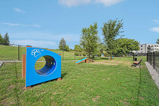 A playground with a blue tunnel and a slide.