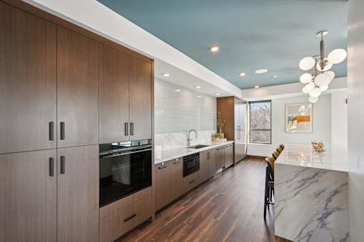 A modern kitchen with wooden cabinets and marble countertops.