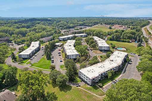 A large, green campus with a few buildings and a parking lot.