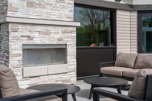 A patio with a stone fireplace and furniture.