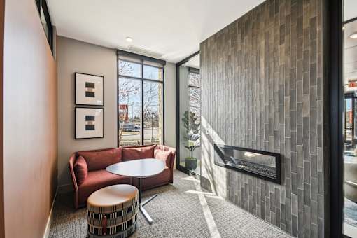 A modern waiting area with a red couch, a round table, and a wooden wall.