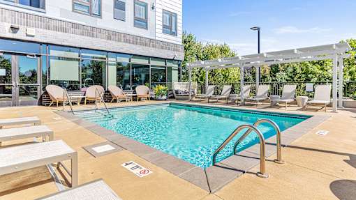 a swimming pool with lounge chairs and a building with glass windows