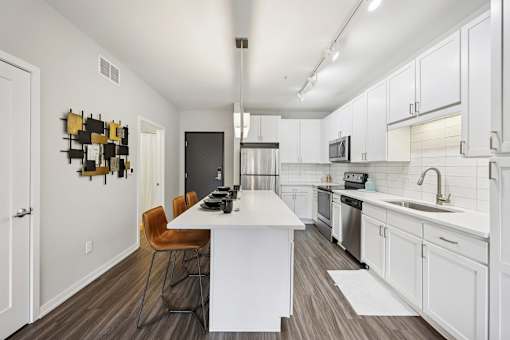 A modern kitchen with a white island and wooden floors.