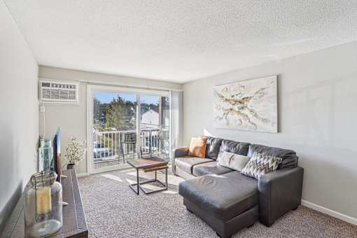 A living room with a grey couch and a painting on the wall.