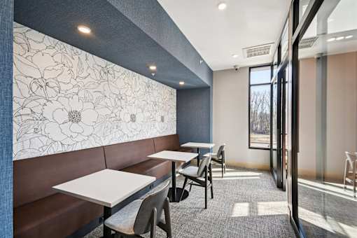 A room with a wallpapered wall and a table with chairs.