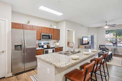 A kitchen with a refrigerator, microwave, and sink.