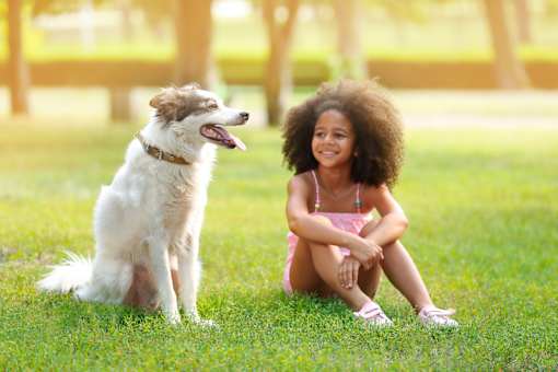 a girl sitting on the grass with her dog
