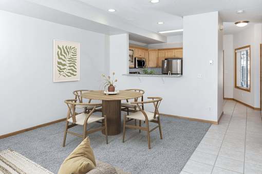 a dining area with a table and chairs and a kitchen in the background