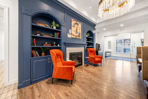 A living room with a fireplace and two orange chairs.
