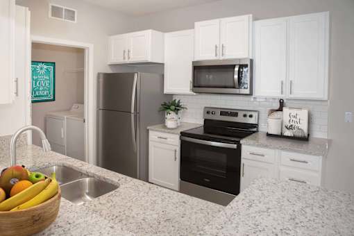 Upgraded kitchen with white cabinetry, stainless steel appliances, and granite countertops.