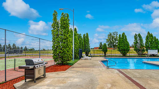 a grill next to a swimming pool with a chain link fence